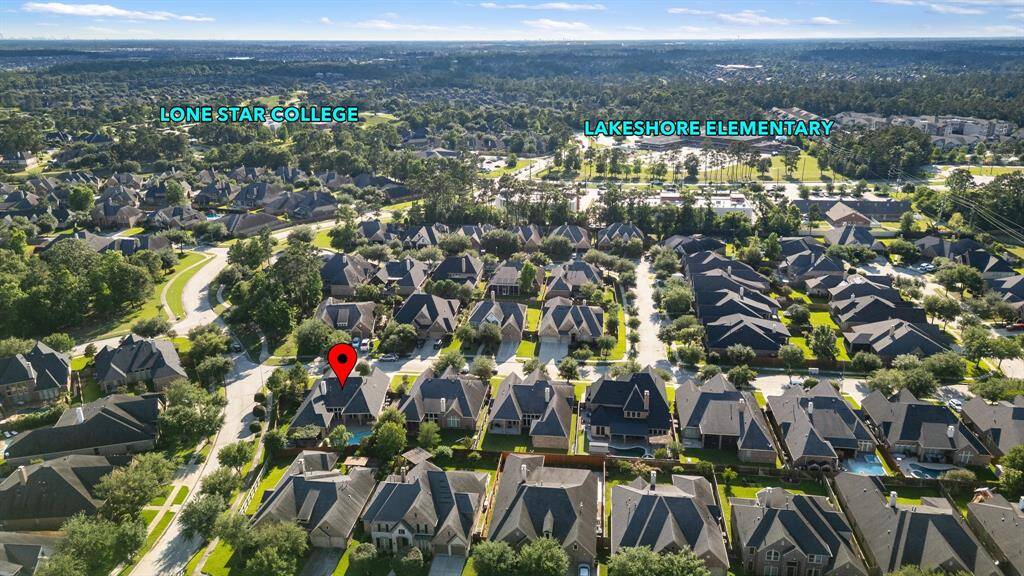 This aerial photo showcases a suburban neighborhood with a marked property. It's well-situated near Lone Star College and Lakeshore Elementary, highlighting convenient access to educational facilities. The area is lush with greenery and features uniform, well-maintained homes.