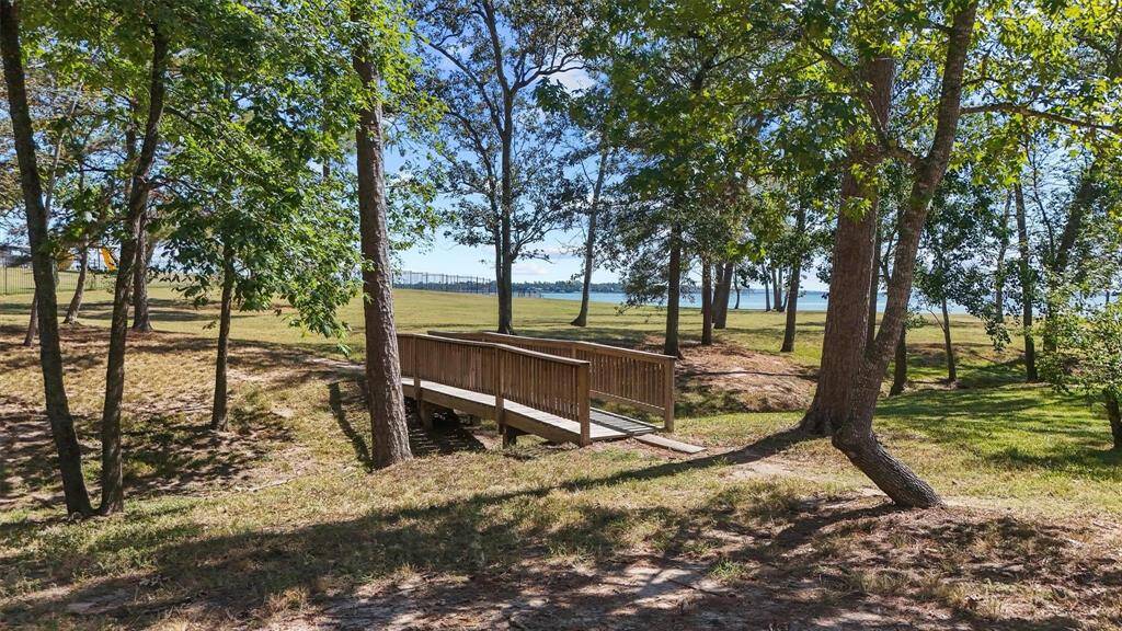 Discover tranquility in this picturesque setting, featuring a charming wooden bridge leading to an open field with a serene water view—ideal for nature enthusiasts.
