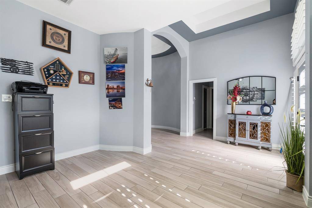 This inviting entryway features light wood flooring, soft gray walls, and abundant natural light.  The space is open and welcoming, perfect for displaying personal touches.