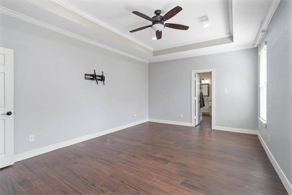 This home offers a split floor plan placing the primary room at the oppose side of the home. This bedroom offers soundproof walls meaning there is extra added insulation within the interior walls allowing for noise reduction and extra privacy. Notice the tray ceiling above housing a fan that is also operated via remote.