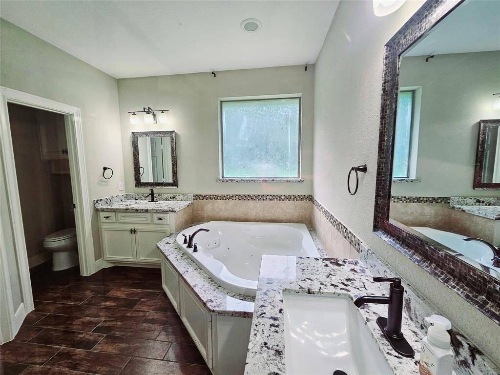 Step into the primary bath featuring separate vanities, a jetted tub for relaxation and a standalone shower.          A smaller closet is located within this bathroom to the left.  New sink faucets installed May 2025 and never used.