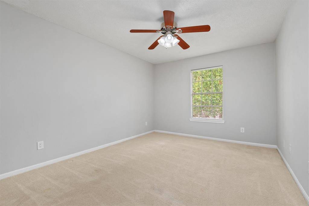 This secondary bedroom includes a large window and a neutral palette, ready for personalization. All bedrooms have ceiling fans to keep you cool in the hot summer months.
