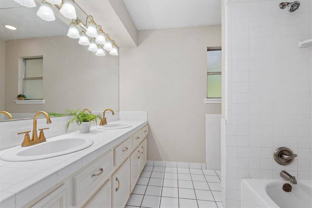 This is the second full bathroom upstairs featuring tile flooring, modern fixtures, and a shower/tub combo.