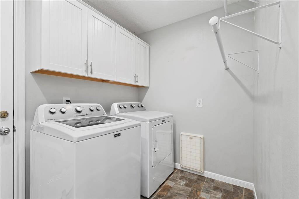 Dedicated laundry room with built-in cabinetry and space for full-size appliances, offering both convenience and storage.