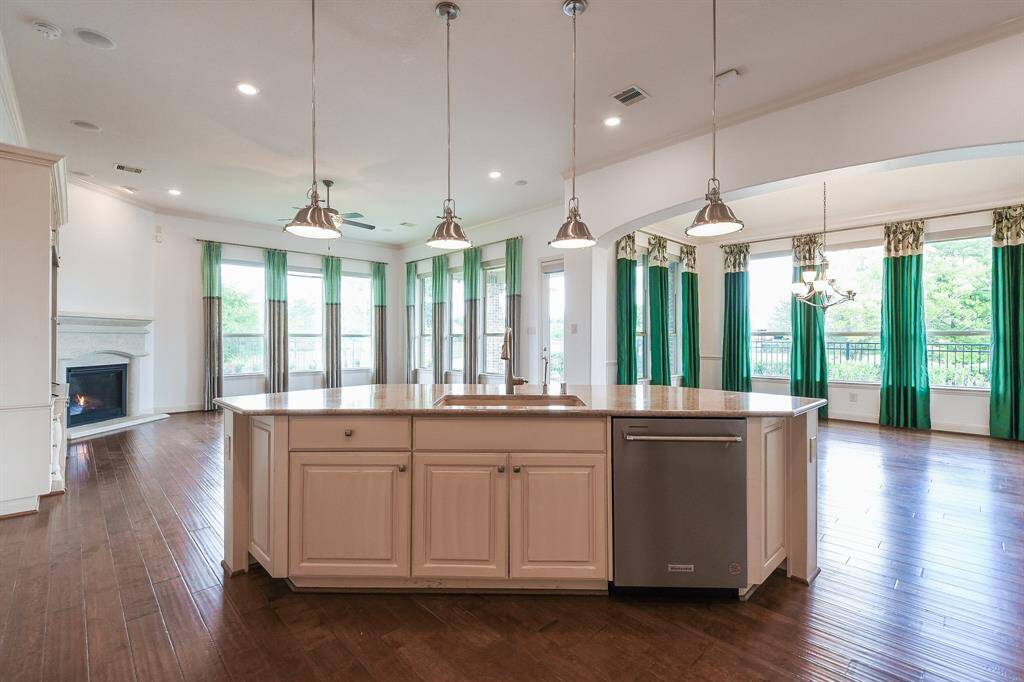 A contemporary vibe delivers sophisticated pendant lighting over the huge, oversized island, housing the sink, and traditional cabinetry, below.