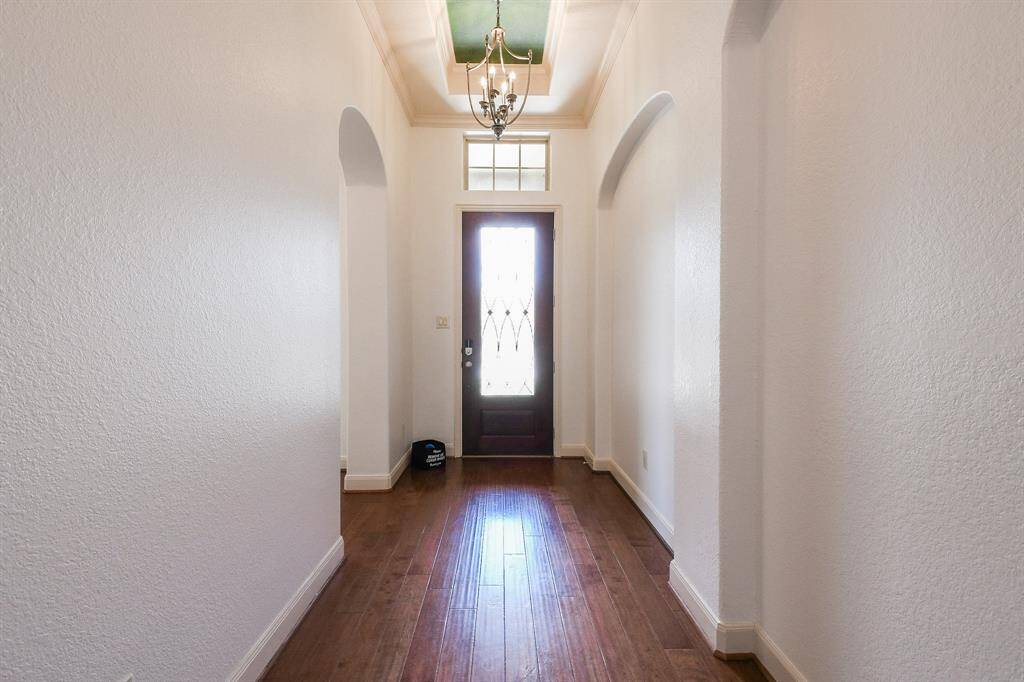 How peaceful is this view of the front entry from the inside, with high ceiling, pale walls and shining engineered wood flooring? (Note the arched doorways and wall niche.)