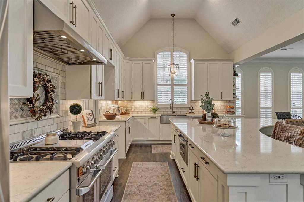 Stunning custom kitchen equipped with a dual-fuel range, stainless steel appliances, built-in microwave drawer, farm sink & oversized quartz countertop island.