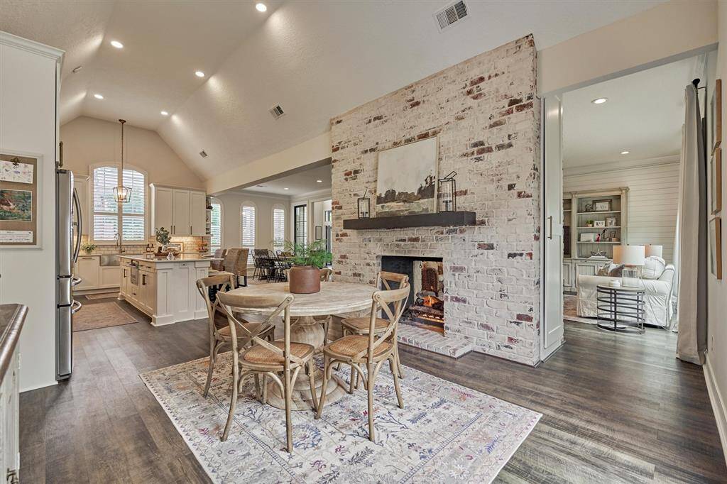 Breakfast room with charming brick dual-sided fireplace and natural lighting. Media storage cabinet at end of fireplace.