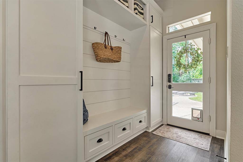 Mudroom with custom cabinetry, hooks for organization, bench seating & ample storage.