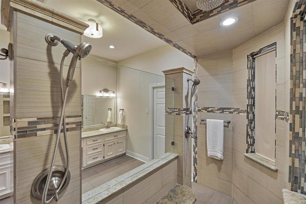 Primary bathroom with a spacious, tiled, dual entry walk-in shower that includes dual shower heads, rain head, plus two hand sprayers & accent tile work.