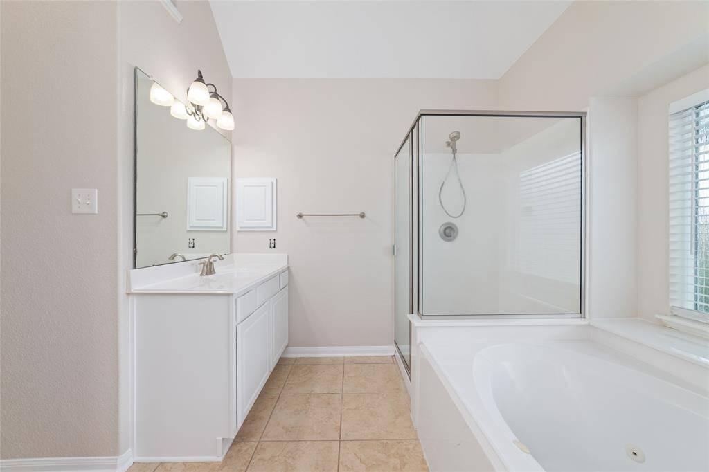 This bathroom features a clean, modern design with neutral tones. It includes a spacious walk-in shower, a large soaking tub, and a vanity with ample counter space.