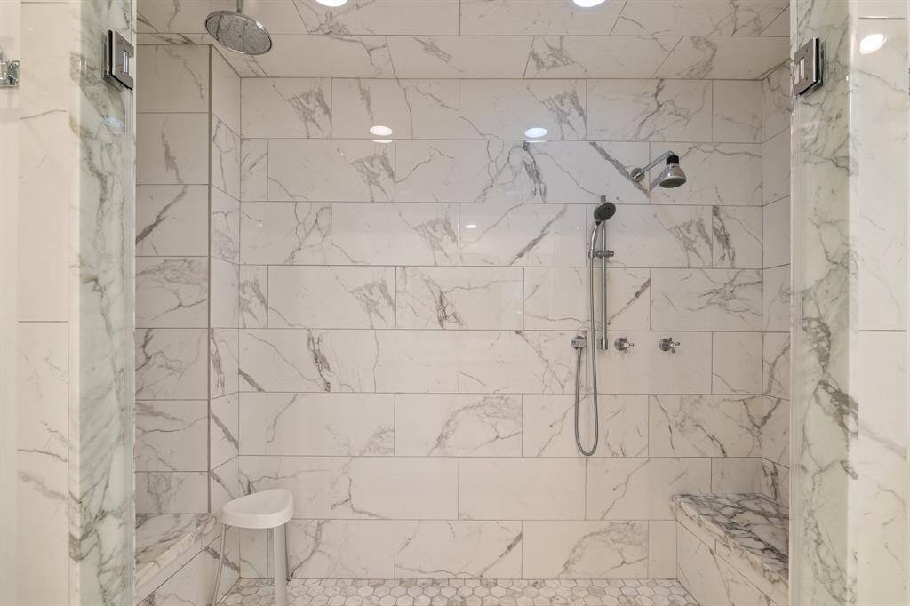 A close up image of the Primary shower clad with Calcutta marble, dual benches and 3-showerheads (rain style, wall shower and hand held).  Great place to start you day or end your day....or both!
