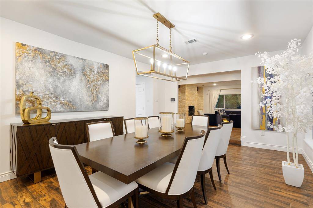 A view of the Dining Room (20 x 13) towards the Entry and the Kitchen (through the opening on the left of the image).  Beautiful, clean lines with porcelain wood style flooring, stylish lighting and access to the rest of the first floor.  This Dining Room is ready for your large or small dinner parties or holiday meals.  Time to make some memories.