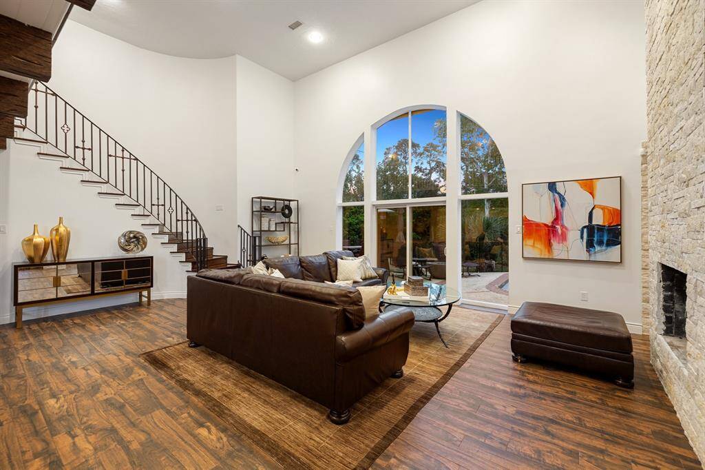 The 2-story Family Room as viewed toward the sweeping staircase, the large, arched window (with automatic storm shutter) and the dual sided gas log fireplace with stone accent wall.  Gorgeous!
