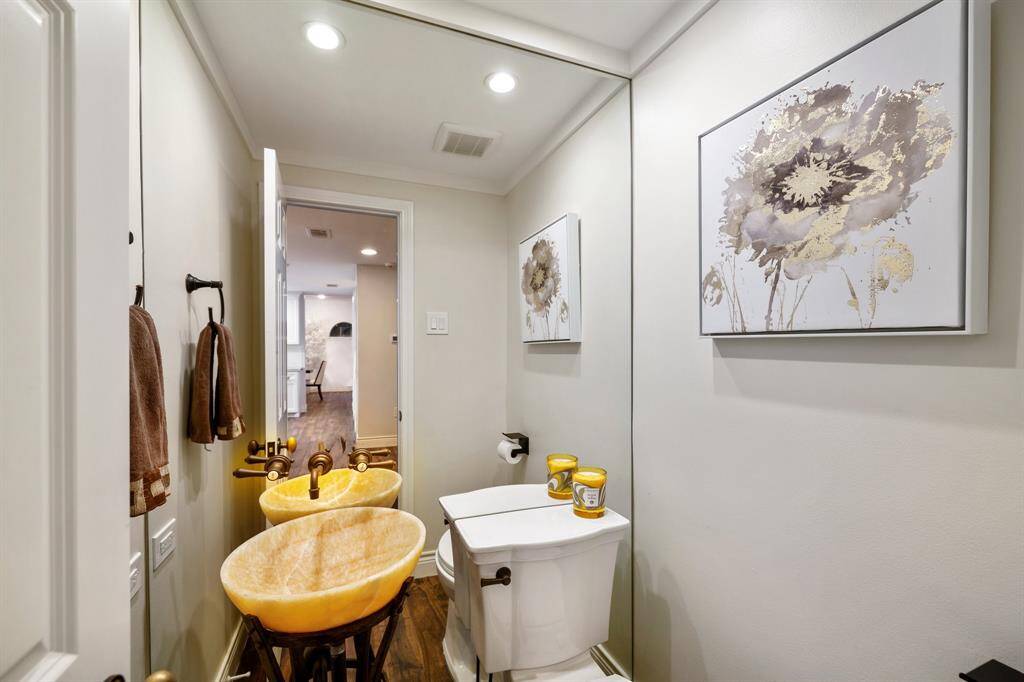 The Powder Bath is located conveniently off the Family Room and Breakfast Room adjacent to the Laundry Room. Note the designer onyx basin and American Standard toilet.