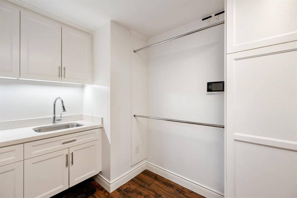 This view of the expanded Laundry Room shows the soaping sink and solid surface counter and backsplash, under cabinet lighting, double hanging rods and upper/lower cabinets and drawers.  Functional and beautiful.