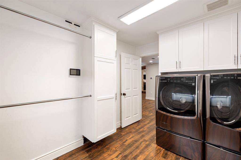 This awesome Laundry Room (13 x 8) was expanded in 2018 (Per Seller).  There is a great double hanging bar for items coming right out of the dryer or for items that are air dried.  Lots of built-in cabinets for cleaning supplies and bulk storage.  The soaping sink is out of view in this image.