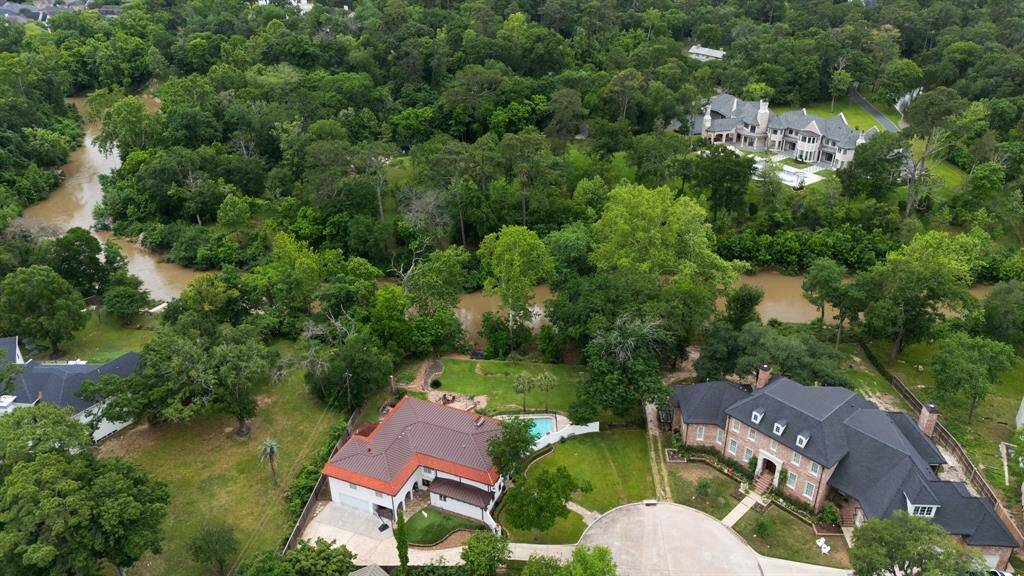 This drone image focuses on the covered loggia that opens to the turfed yard and has access to the interior of the home through the Laundry Room.  Lots of extra parking behind the driveway gate.