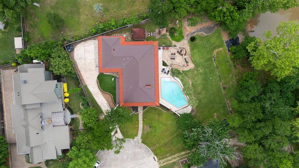 This drone image shows the location of 2 Warrenton on the cul-de-sac, the gated driveway and turfed side yard on the left, the swimming pool, patio and terraced yard to the bayou on the right and the vegetable and herb garden with the smoker behind the patio.  Quite a compound, right?