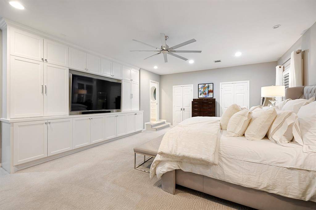 A view of the Primary Bedroom toward the wall of built-in cabinets (upper and lower).  The door at the far end of the built-in leads to the gorgeous Primary Bath.  Truly a beautiful owner's retreat.