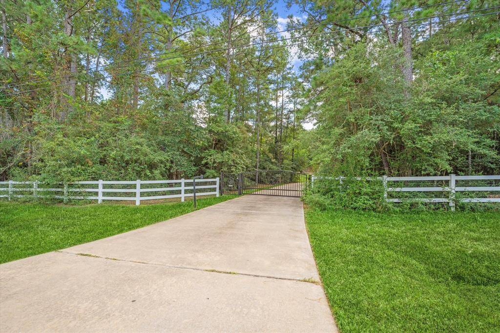 Private driveway with electric gate lined with trees, offering a grand entrance to the property.