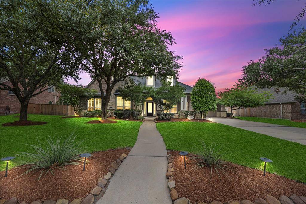 Charming 3-bedroom, 3-bath home sits on a huge 20,426 sq ft lot with 2,966 sq ft of living space. A front path, lush lawn, and mature trees create a warm welcome.