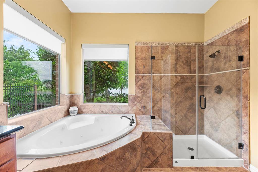 Primary bathroom featuring the corner bathtub and separate glass-enclosed shower.