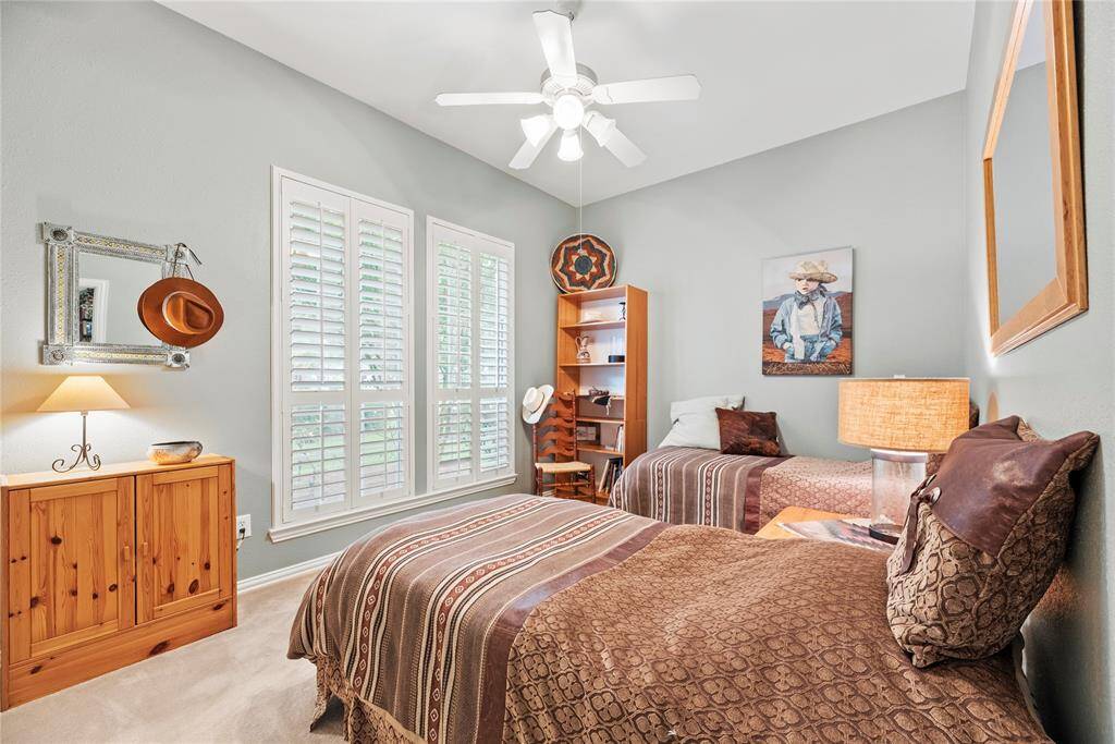 Second bedroom featuring ceiling fan, and ample natural light from shuttered windows, and carpet flooring.