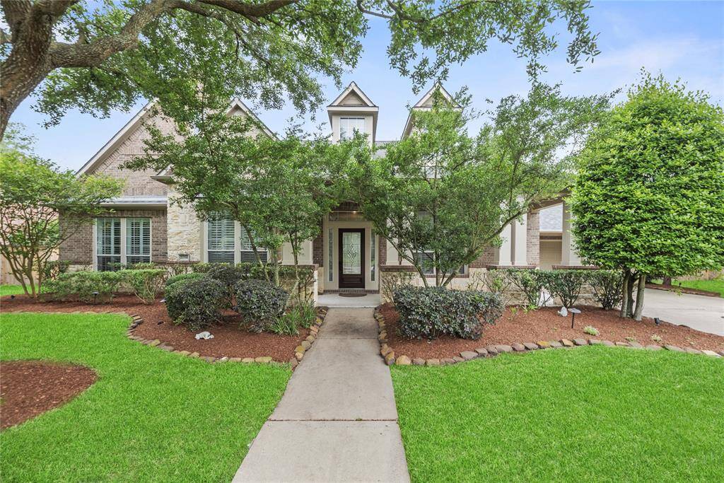 Another view of the front exterior highlights the beautifully landscaped yard and the inviting walkway leading to the front porch entry.