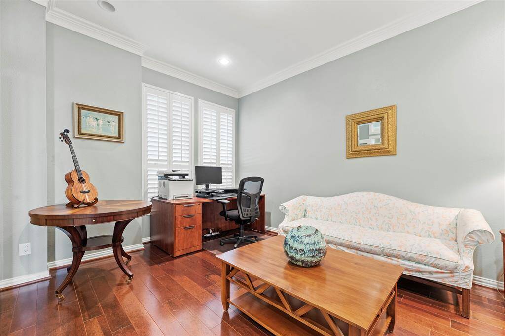 The home office features rich wood flooring and large windows that fill the space with natural light.