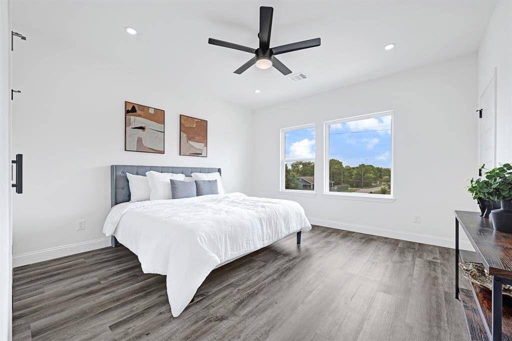 Master bedroom featuring abundant natural light, sleek hardwood floors, and modern design elements.