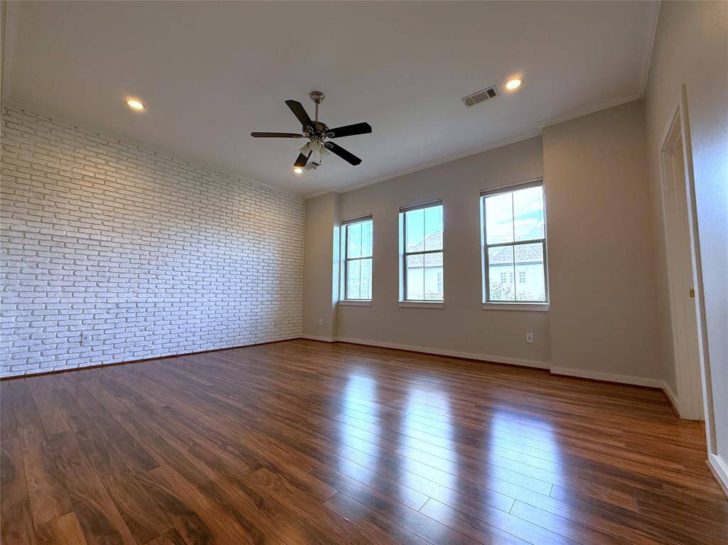 On the 3rd floor, at the top of the stairs, is the primary suite. Celling fan, faux brick wall, recessed lighting and top-down, bottom-up blinds.