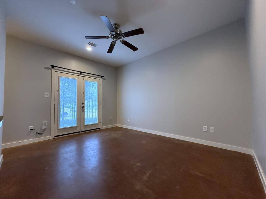 The first floor bedroom with ceiling fan, concrete floor, recessed lighting & glass paned French doors with internal blinds.