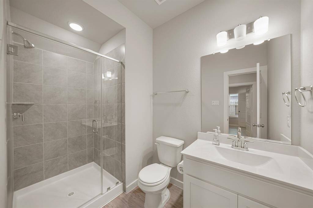 Secondary bathroom with vinyl floors, granite countertops, recessed lighting, and a glass enclosed walk-in shower with gorgeous tile walls.