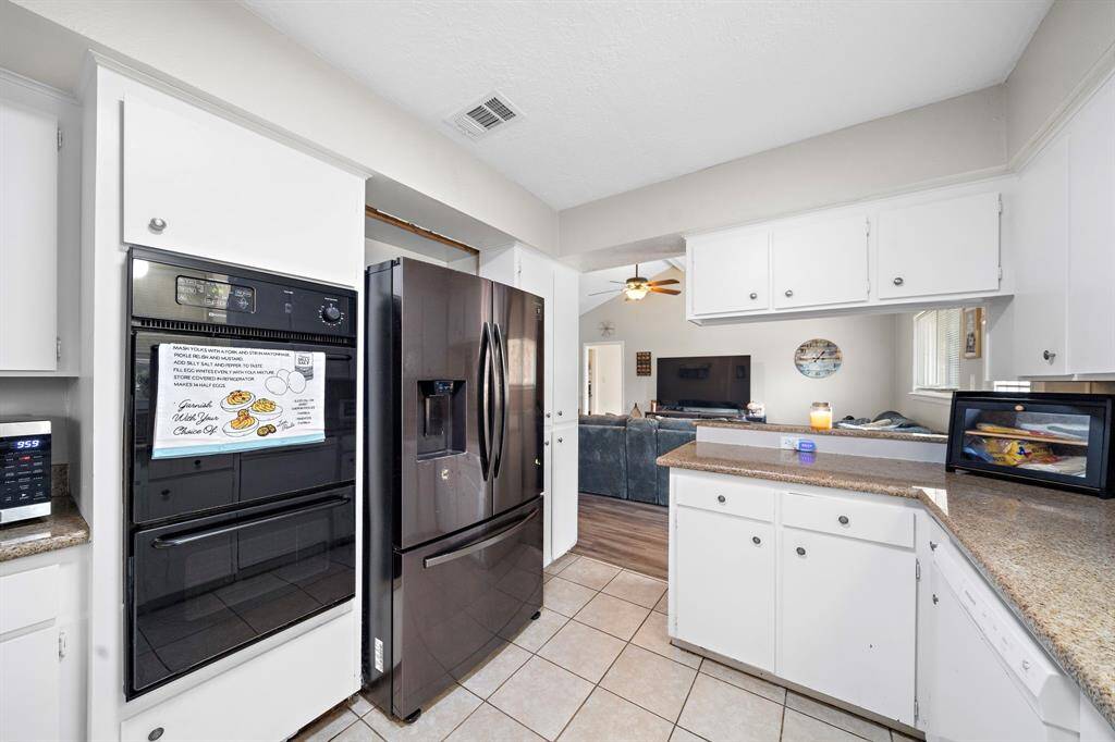 Bright kitchen with white cabinetry, sleek countertops, and modern appliances including a double oven.