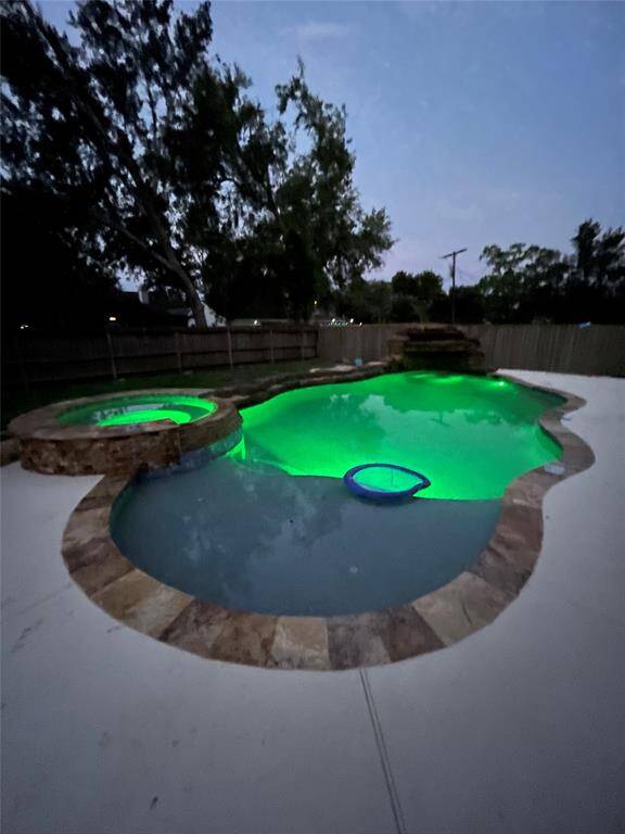 Night time view of the pool and spa with light features.
