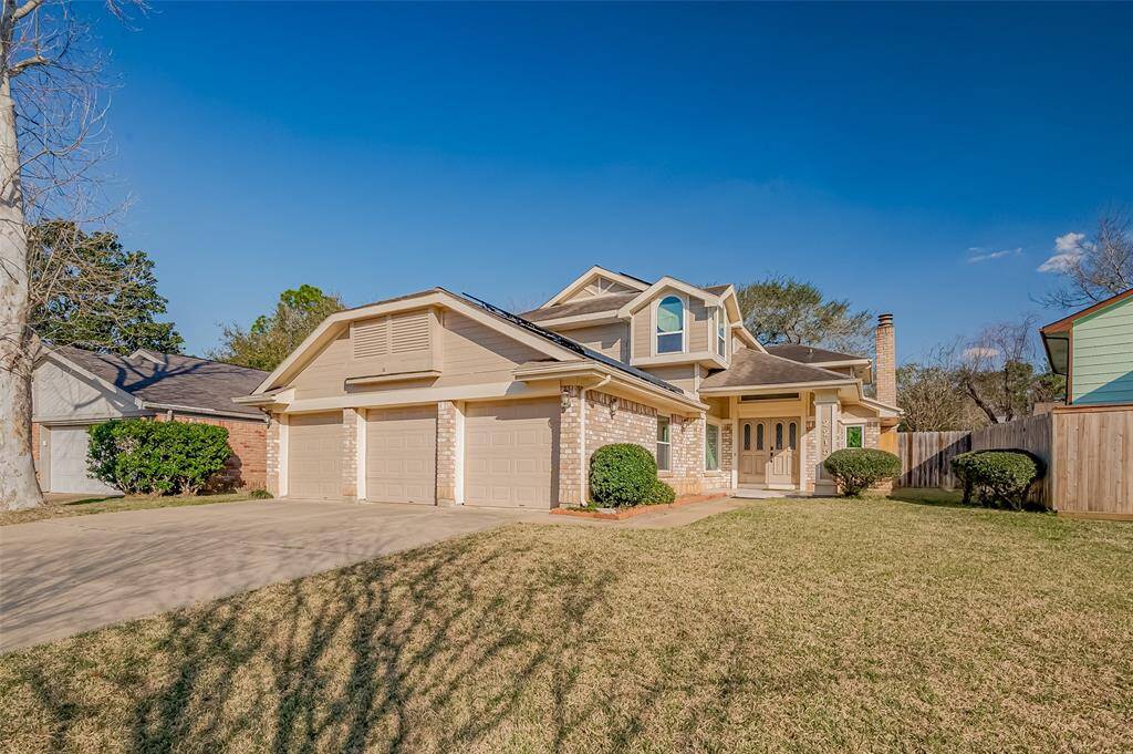 This inviting home features a classic two-story design with a three-car garage. The exterior showcases a combination of brick and siding, surrounded by a well-maintained lawn and shrubs. A spacious driveway leads to the main entrance, offering great curb appeal in a peaceful neighborhood setting.
