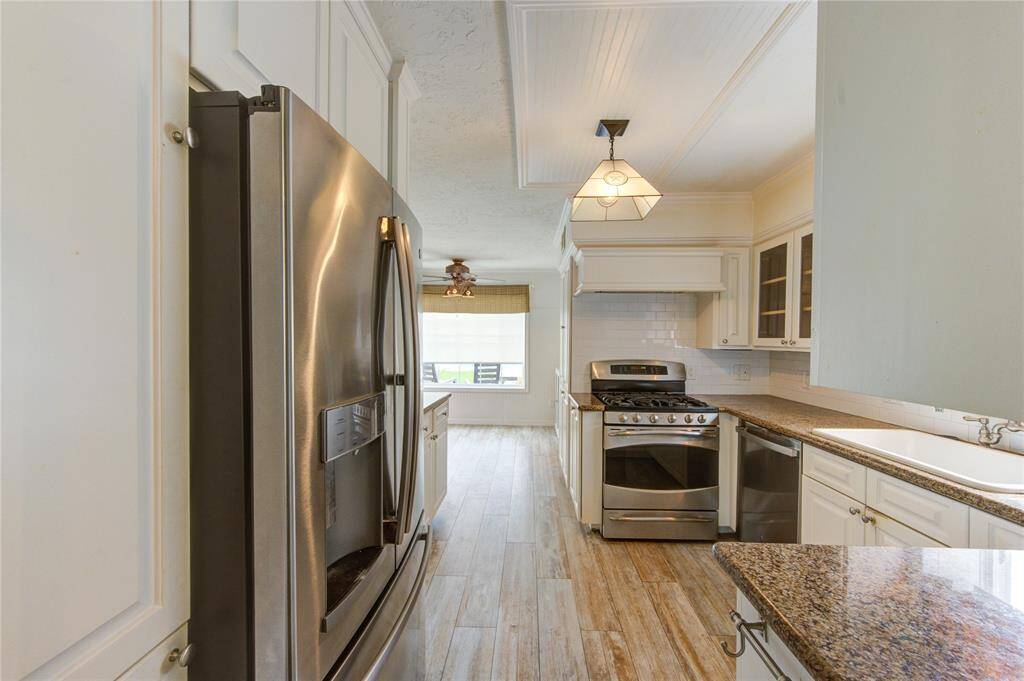 This bright and inviting kitchen features stainless steel appliances, granite countertops, and stylish wood-look tile flooring that flows into a spacious breakfast room