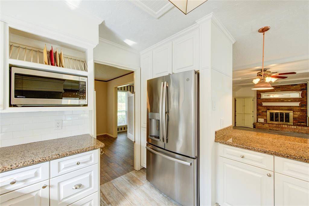 Enjoy the kitchen with granite countertops, custom cabinetry with built-in plate storage, and opens seamlessly to a cozy living area with a brick fireplace and warm natural light
