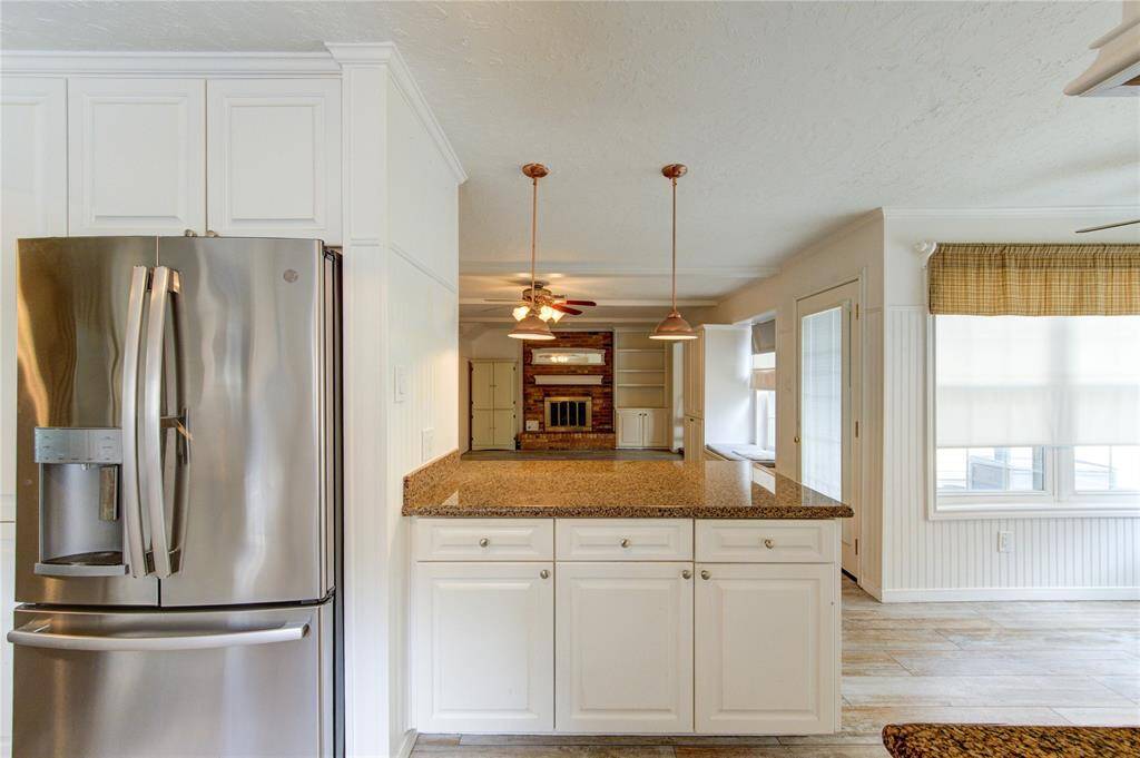 Enjoy open-concept living from the kitchen, overlooking the cozy living room with built-in shelving and a rustic brick fireplace centerpiece.
