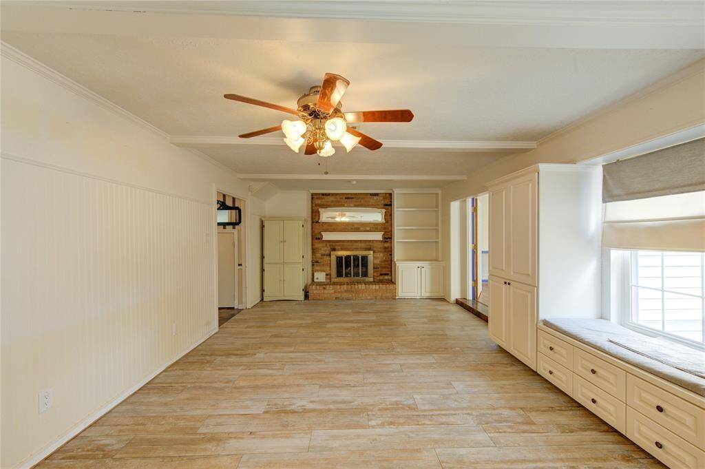 The living room offers built-in cabinetry and shelving, a charming window seat with extra storage, and a classic brick fireplace as the focal point