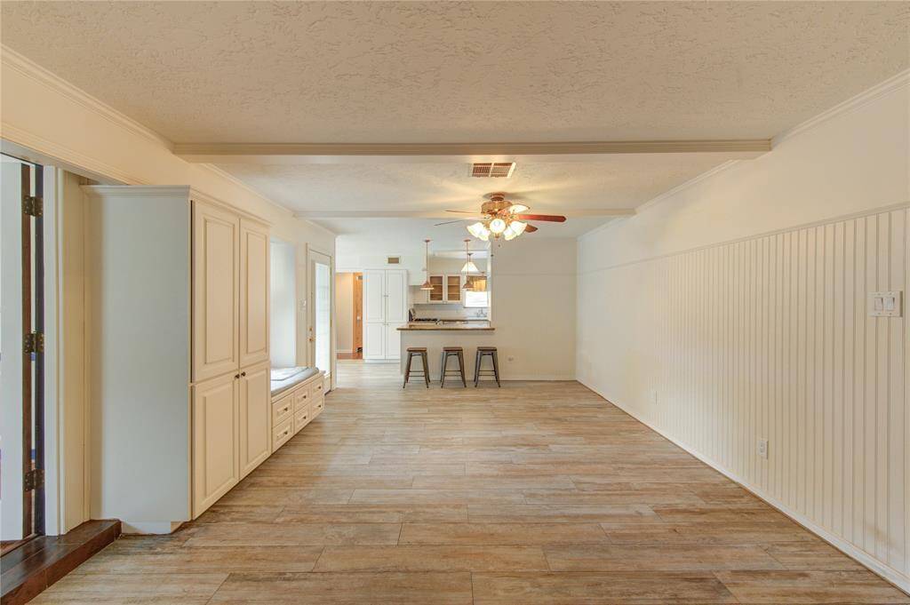 This spacious open living area features classic beadboard wainscoting for added charm, a built-in window seat with storage