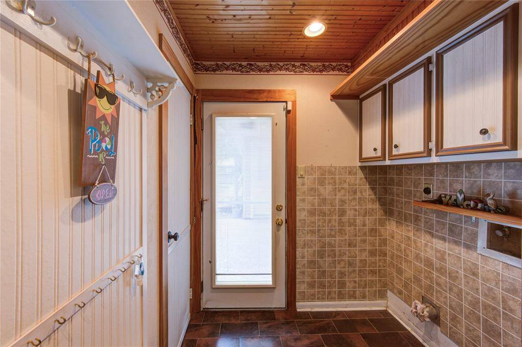 The utility room offers built-in cabinetry, wall hooks for storage, and direct access to the backyard—perfect for managing pool gear or outdoor essentials.
