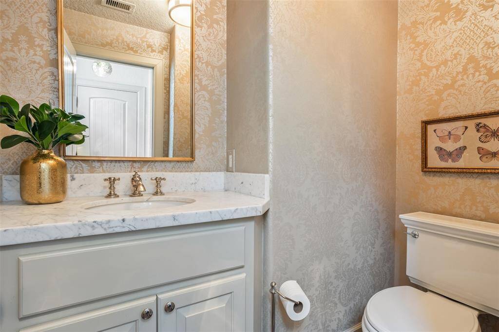 Gracefully appointed with marble countertops and designer wallpaper, this first-floor powder room offers a refined touch for guests. Conveniently located between the living and dining areas, it blends function with timeless style.
