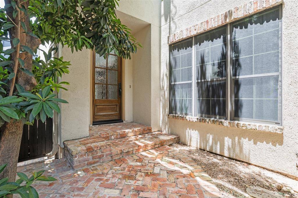 Tucked beneath the shade of a graceful tree, the brick-lined entryway offers a peaceful welcome home. A secured cast iron gate leads to the private back patio, while the large window invites natural light into the cozy breakfast nook—blending charm, comfort, and quiet sophistication from the moment you arrive.