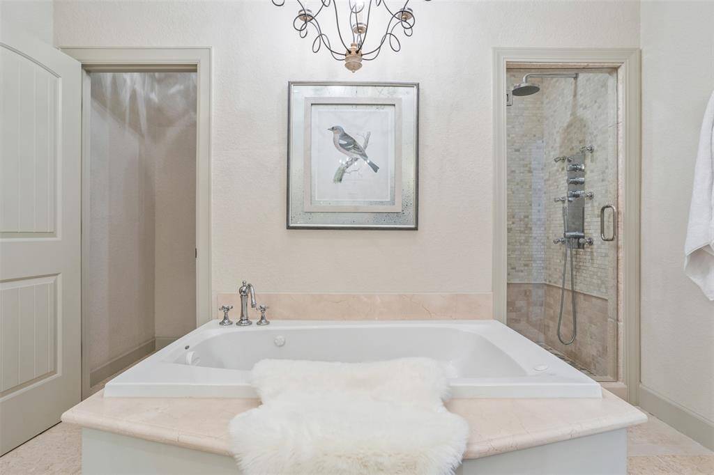 Indulge in spa-like luxury with a frameless glass shower, jetted soaking tub, and private water closet—all thoughtfully arranged for comfort and elegance. A walk-in closet just beyond completes this serene primary bath retreat, offering both beauty and practicality.