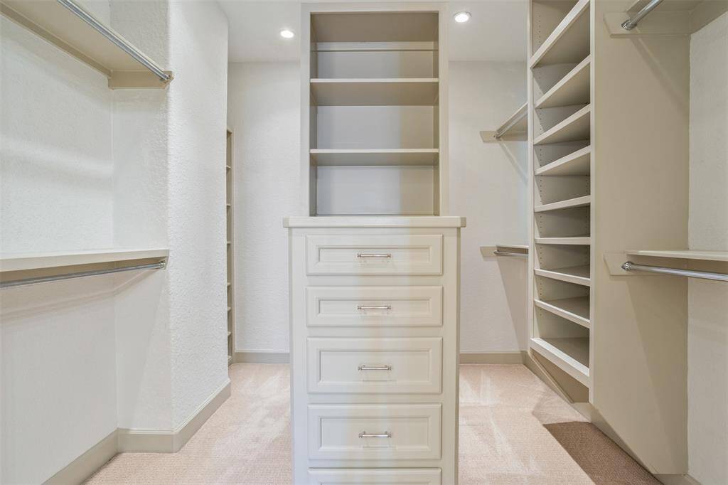 Impressively designed with ten clothing racks, built-in shelving, and a center island with drawers, this spacious walk-in closet offers elegant organization for every wardrobe. A perfect balance of form and function within your private suite.