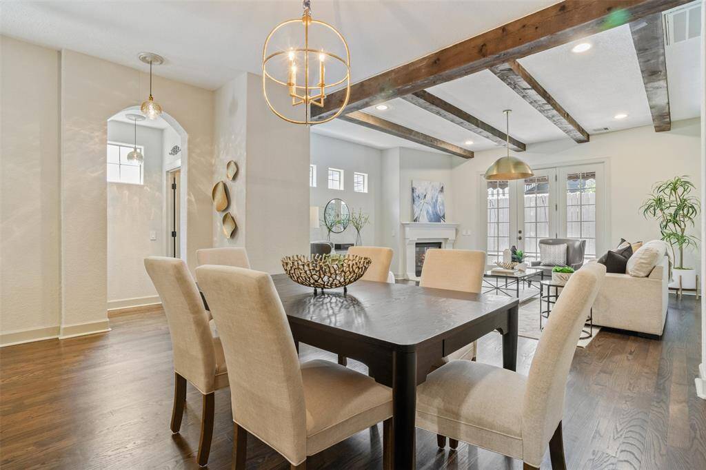 Thoughtfully designed for effortless entertaining, the dining room flows seamlessly into the inviting living space. Exposed wood beams, elegant lighting, and a cozy fireplace create a warm, sophisticated ambiance—perfect for intimate dinners or lively gatherings alike.