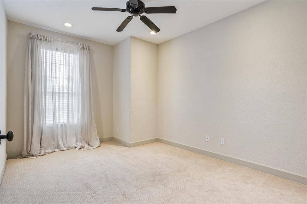 This secondary bedroom offers a blank canvas with soft neutral tones, plush carpet, recessed lighting, and a ceiling fan. Whether used as a guest room, home office, or creative space, it’s ready to adapt to your needs.