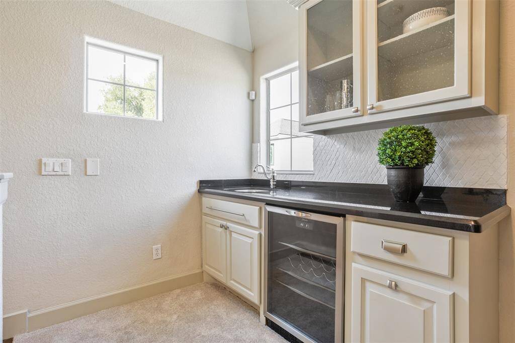 Tucked on the third level, this stylish wet bar features sleek black countertops, a built-in wine fridge, and upper glass-front cabinetry—perfect for entertaining, winding down, or elevating your movie or game night experience.